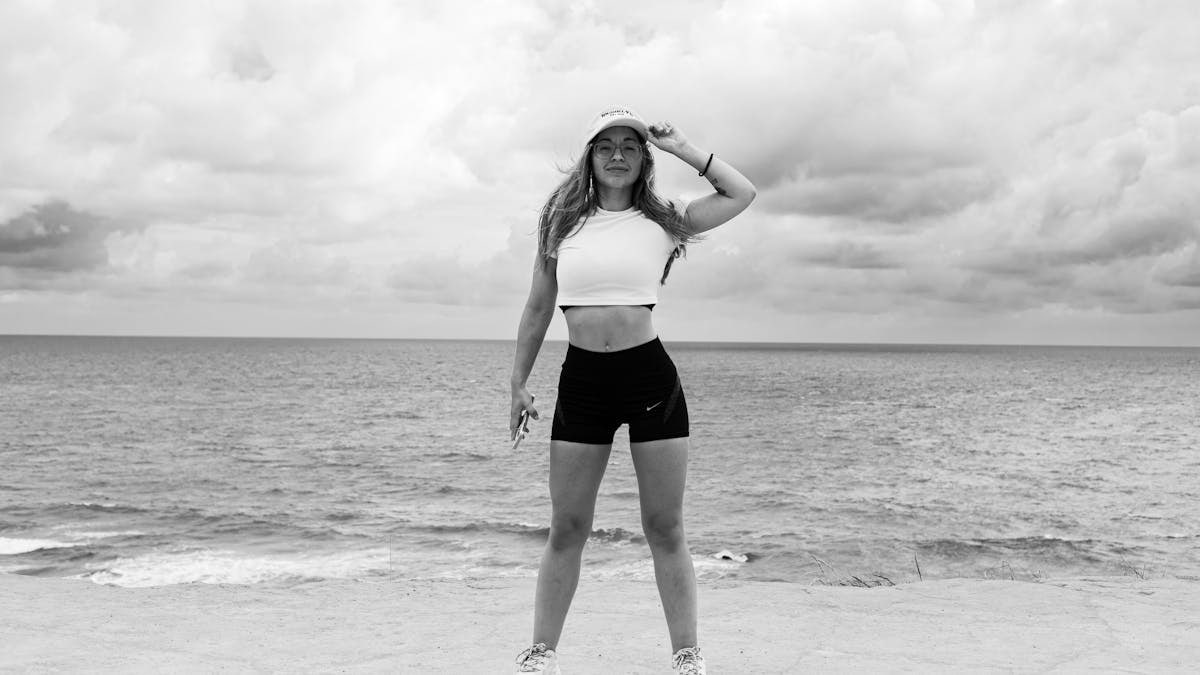 Black and white photo of a woman standing at the beach in Natal, Brazil, enjoying the ocean view.